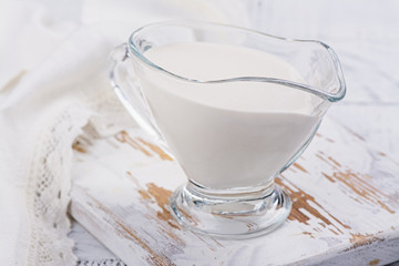 Fresh homemade sour creme on white wooden table. Farm product. Copy space