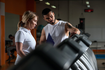 Blonde woman working out in gym with fitness coach