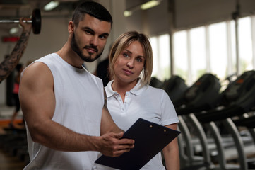 Blonde female with fitness trainer in gym