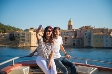 Fototapeta na wymiar Smiling Couple Happy Taking Selfie on Boat Ride at Saint-Tropez, Cote d'Azur, France