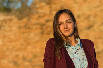 a beautiful girl poses in front of a medieval fortress at sunset