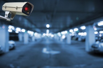 CCTV, security indoor camera system operating in underground car parking garage area, blue color...