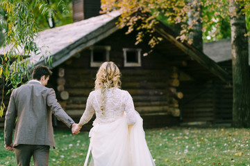 Bride and groom go to wooden home in the forest. Autumn wedding. Artwork - 178847815