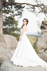 Beautiful bride with a bouquet posing in forest with rocks. Outdoors