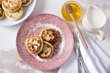 Cottage cheese pancakes, homemade syrniki with honey and sour cream.
