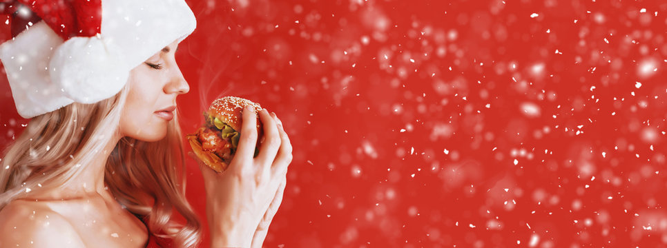 girl in red dress and santa hat with burger in hands