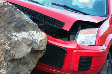 The red car hit the falling stone on the road