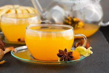 sea buckthorn tea with cinnamon and spices in beautiful glass cup. Natural light, selective focus. 