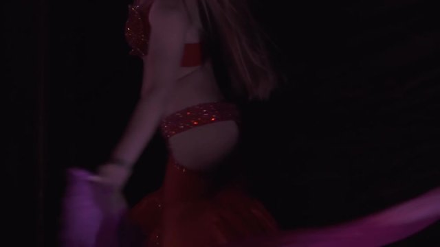 Beautiful belly dancer, night. Beautiful young woman belly dancer dancing belly movement, modern, on black background, slow motion. Close up.