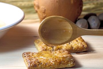 liquid fresh honey dripping from wooden spoon into biscuit