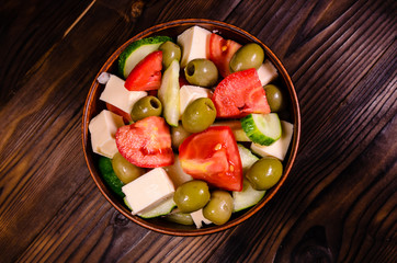 Greek salad in a bowl on wooden table. Top view