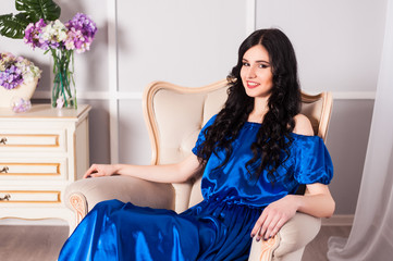 young woman in elegant blue gray evening dress indoors with beautiful interior