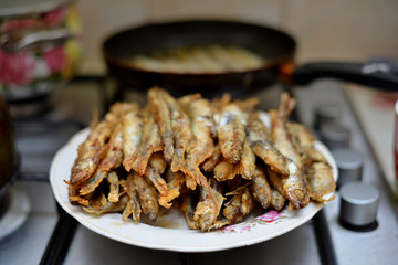 Fried smelt in a frying pan on the table with spices, lime and thyme. Small crispy fish. Selective focus