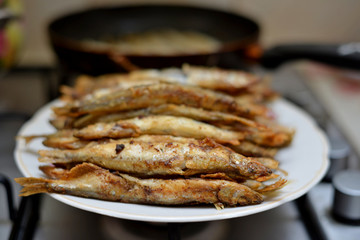 Fried smelt in a frying pan on the table with spices, lime and thyme. Small crispy fish. Selective focus
