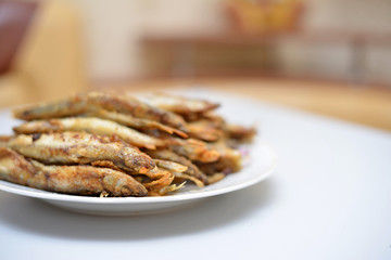 Fried smelt in a frying pan on the table with spices, lime and thyme. Small crispy fish. Selective focus