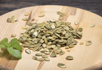 Pumpkin seeds and basil leaves round cutting board