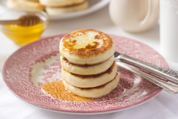 Cottage cheese pancakes, homemade syrniki with honey and sour cream.