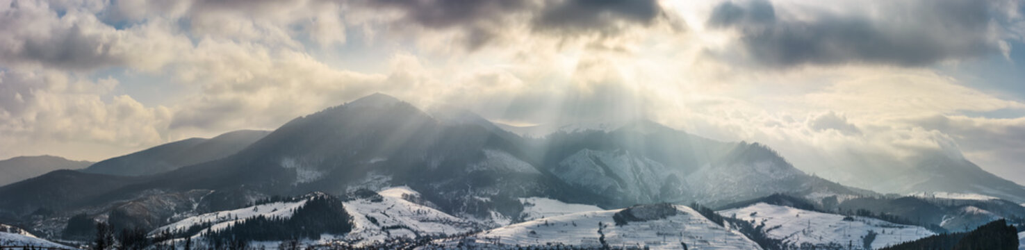 mountain ridge in light beams on cloudy winter day. gorgeous countryside panorama