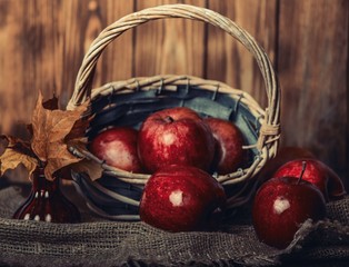 Autumn composition with fresh red apples in a wooden basket on rustic wooden background. Red apples...
