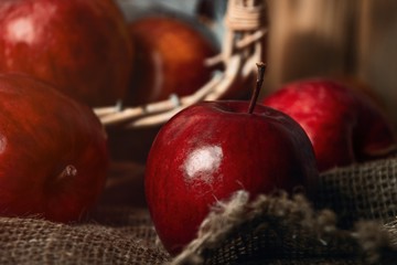 Autumn composition with fresh red apples in a wooden basket on rustic wooden background. Red apples on linen background
