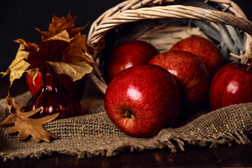 Autumn composition with fresh red apples in a wooden basket on rustic wooden background. Red apples on linen background