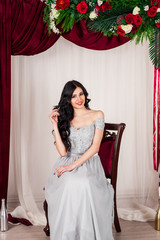 young woman in elegant blue gray evening dress indoors with beautiful interior