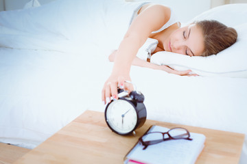 A young woman putting her alarm clock off in the morning.