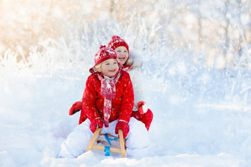 Fototapeta na wymiar Kids play in snow. Winter sleigh ride for children