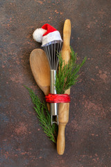 Accessories for New Year's Christmas buns whisk in a santa cap, rolling pin, spoon and eggs, holiday concept on a dark background with copy space view from above