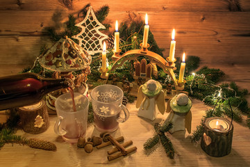 Traditional mulled wine in glasses. Christmas decoration and ornaments on wood background. Festive Christmas alcoholic drink in an atmospheric environment