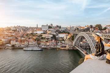 Young woman tourist enjoying great view on the old town and river in Porto city during the sunset...