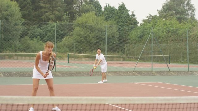  Male & female tennis players serving & scoring a point on outdoor court