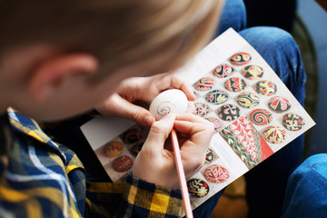 Teen age boy painting a traditional Ukrainian Easter eggs Pysanka