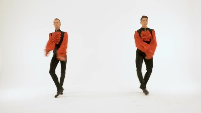 Two men in black suits and red shirts synchronously dance.