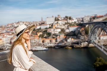 Fototapeta na wymiar Young woman tourist enjoying beautiful cityscape background with famous bridge in Porto city, Portugal
