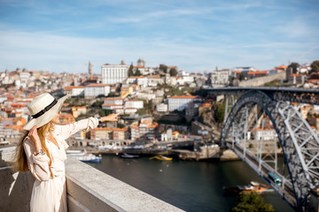 Young woman tourist enjoying beautiful cityscape background with famous bridge in Porto city,...