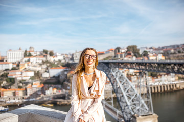 Portrait of a young woman tourist on the beautiful cityscape background with famous bridge in Porto city, Portugal