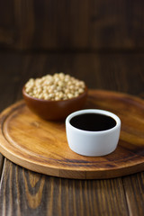 Soy sauce in a white ceramic bowl over wooden board.
