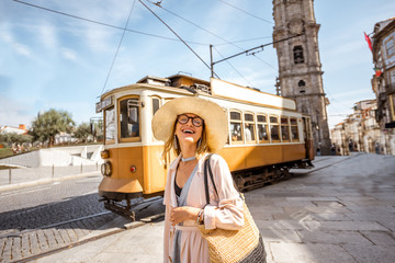 Lifestyle portrait of a woman near the famous old touristic tram on the street in Porto city,...