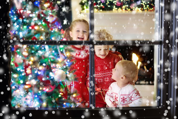 Children at Christmas tree. Kids at fireplace on Xmas eve