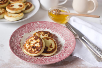 Cottage cheese pancakes, homemade syrniki with honey and sour cream.