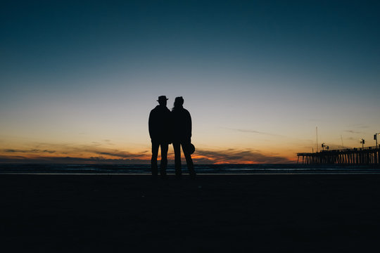 Silhouette couple standing on beach during sunset