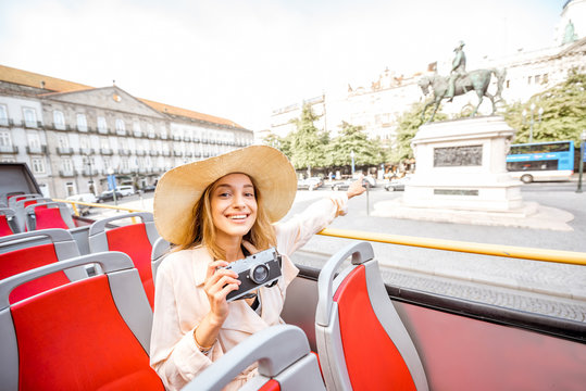 Happy woman having excursion on the open touristic bus standing on the Liberty square in Porto city, Portugal