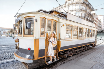 Lifestyle portrait of a woman near the famous old touristic tram on the street in Porto city,...