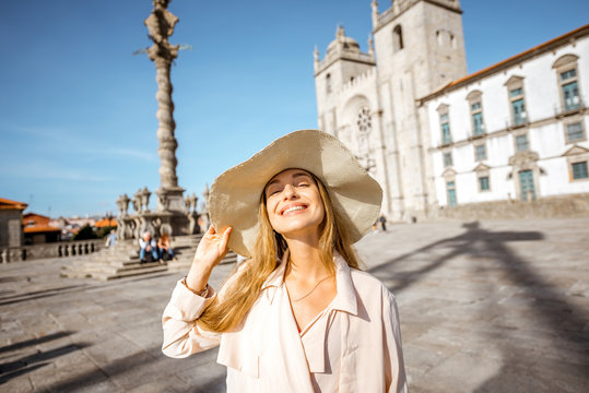 Portrait of a young woman tourist in sunhat standing in front of the main cathedral in Porto city in Portugal