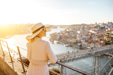 Young woman tourist enjoying beautiful aerial cityscape view with famous bridge during the sunset in Porto city, Portugal