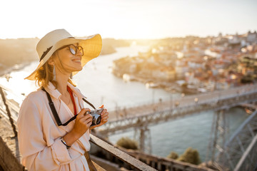 Young woman tourist enjoying beautiful aerial cityscape view with famous bridge during the sunset in Porto city, Portugal