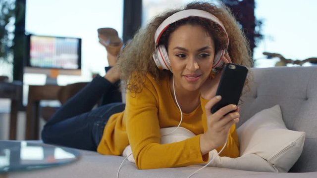 Woman relaxing at home listening to music with smartphone and headphones