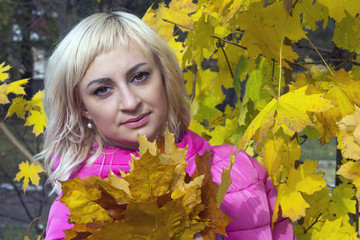 Beautiful girl under a tree with a bouquet of maple leaves