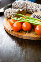 Fresh and ripe asparagus and cherry tomatoes with bread on wooden board.